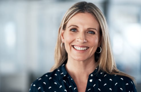 Illustrasjonsbilde. Smilende dame med blondt hår som ser rett inn i kameraet.